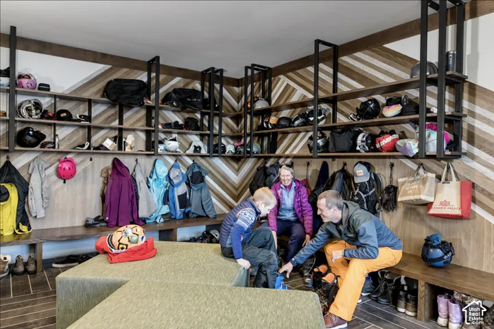 Mudroom featuring chevron wood paneling, floor-to-ceiling built-in shelving, black metal hardware, and natural wood benches