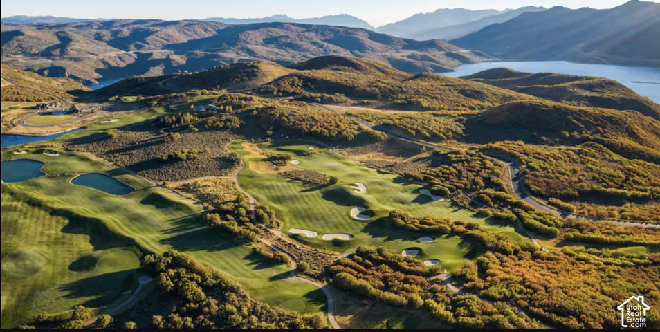 Aerial landscape featuring a manicured golf course, sand bunkers, water hazards, mature native vegetation, and a mountain backdrop