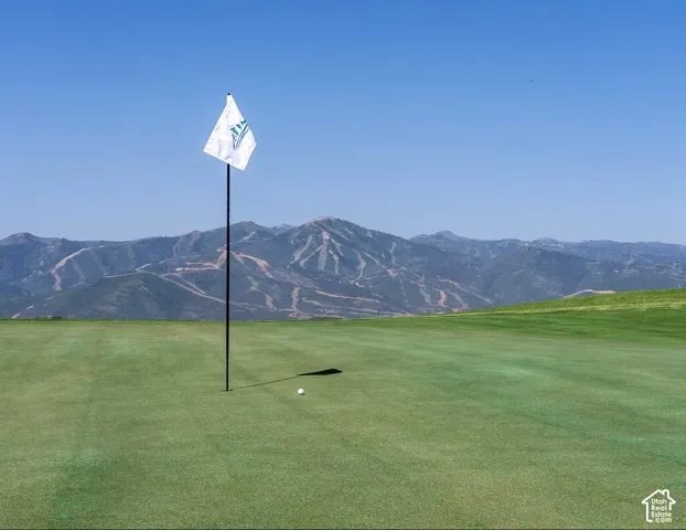 Manicured putting green featuring a pin flag and mountain backdrop