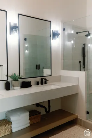 Floating vanity with a light-toned solid surface countertop, undermount sink, matte black widespread faucet, dual rectangular mirrors with black frames, and a glass-enclosed shower featuring matte black fixtures