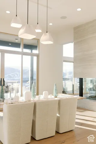 Modern pendant lighting, floor-to-ceiling glass sliding doors, wood-finish flooring, and a full-height stone-clad fireplace