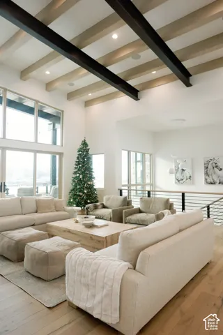 Vaulted ceiling featuring exposed structural steel beams and light-toned ceiling slats, floor-to-ceiling windows, wood-finish flooring, and a metal horizontal-bar stair railing