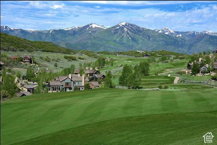 Expansive manicured lawn, golf course terrain, and snow-capped mountain backdrop