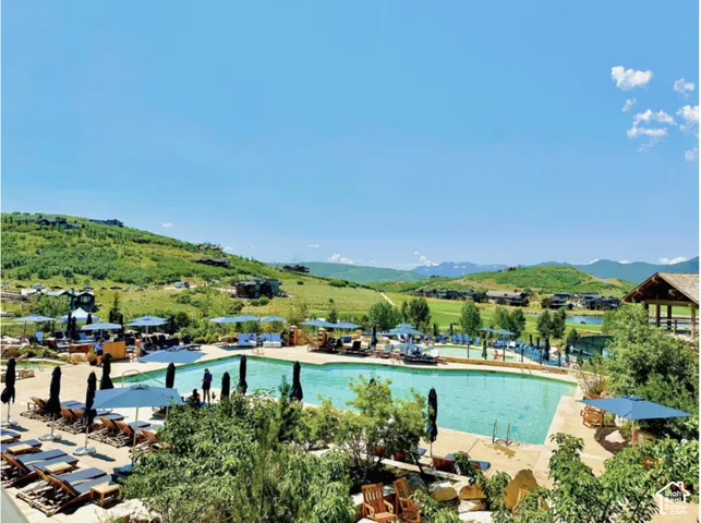 Outdoor swimming pool with stone decking, surrounding mountain landscape, and integrated pavilion structure