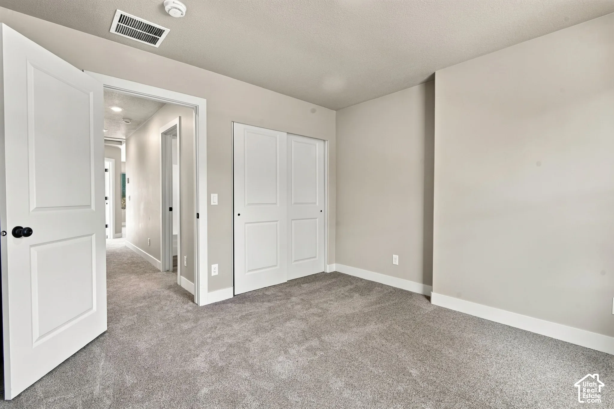 Neutral wall tones, wall-to-wall carpeting, two-panel interior doors, and closet with sliding doors