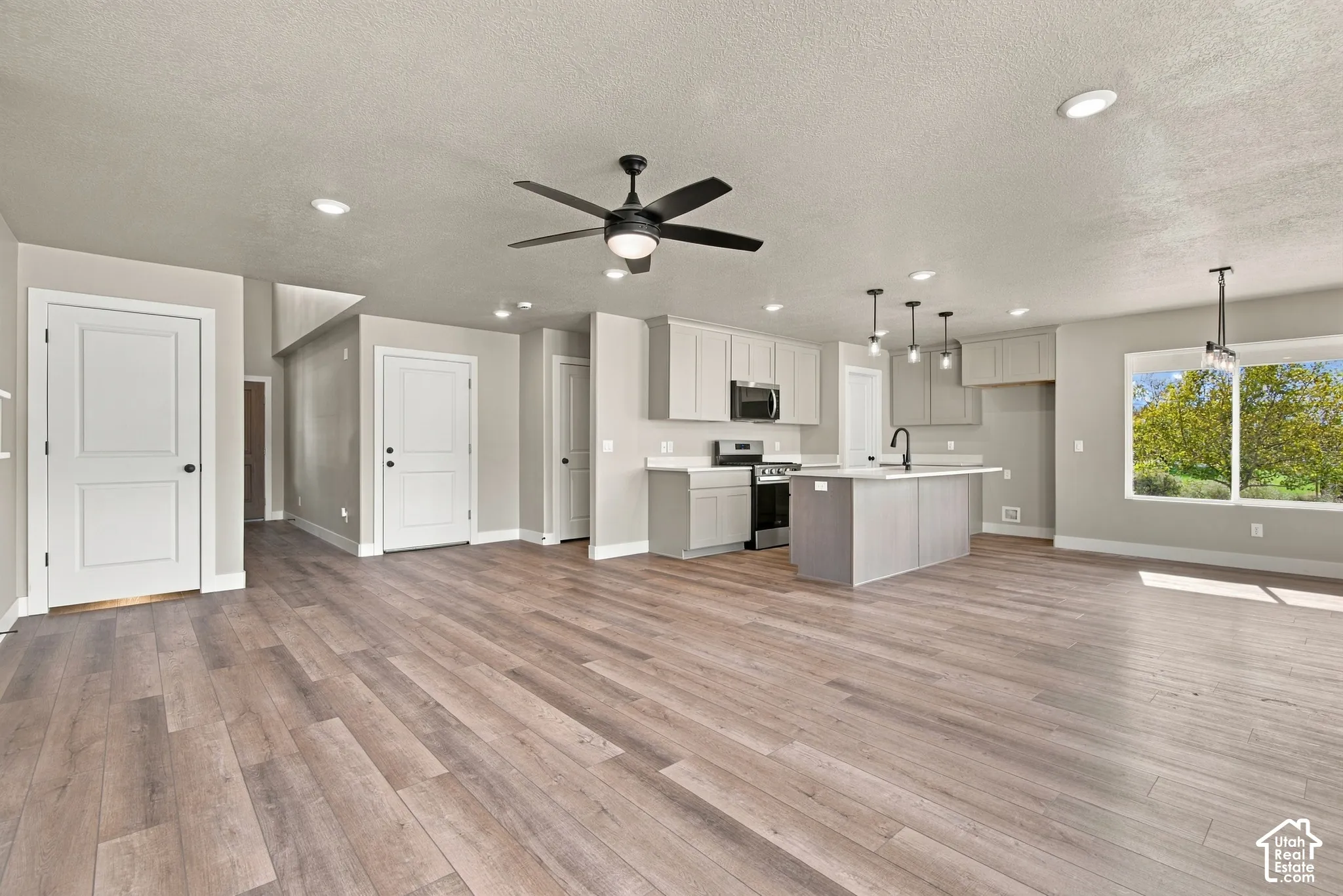 Open concept interior featuring wood-finish flooring, shaker-style cabinetry, a kitchen island, recessed lighting, and a ceiling fan