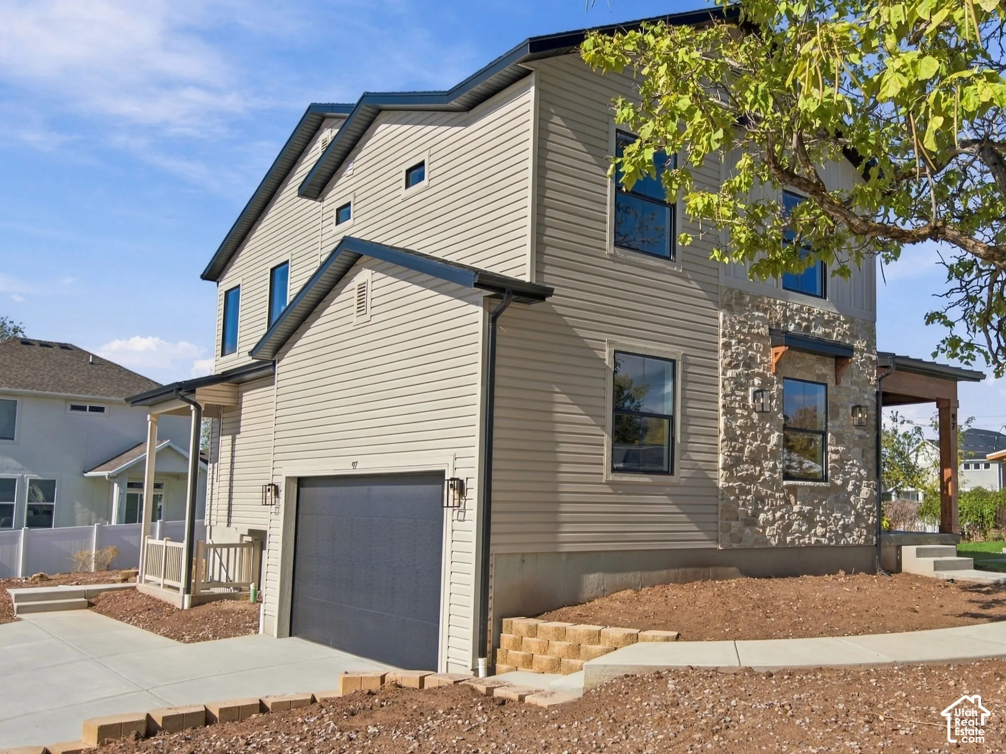 Two-story residence featuring horizontal siding, a stone veneer accent wall, attached garage, and concrete walkway