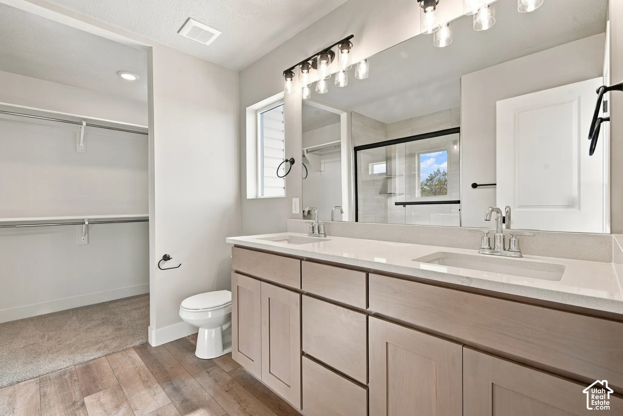 Double vanity with rectangular undermount sinks, stone-finish countertops, shaker-style cabinetry, and a full-width mirror