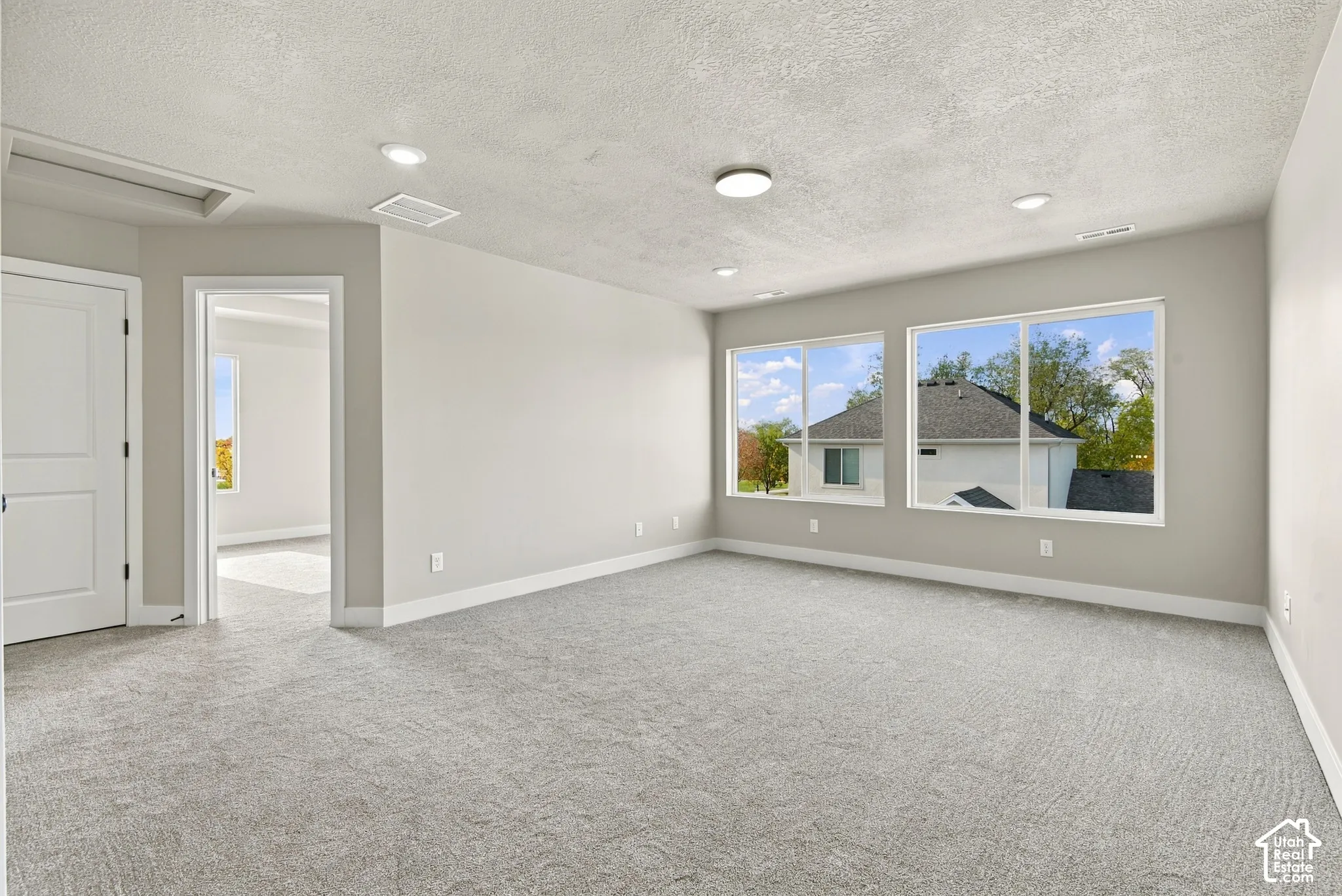 Spacious room featuring neutral carpeting, recessed ceiling lighting, textured ceiling finish, and multiple large windows