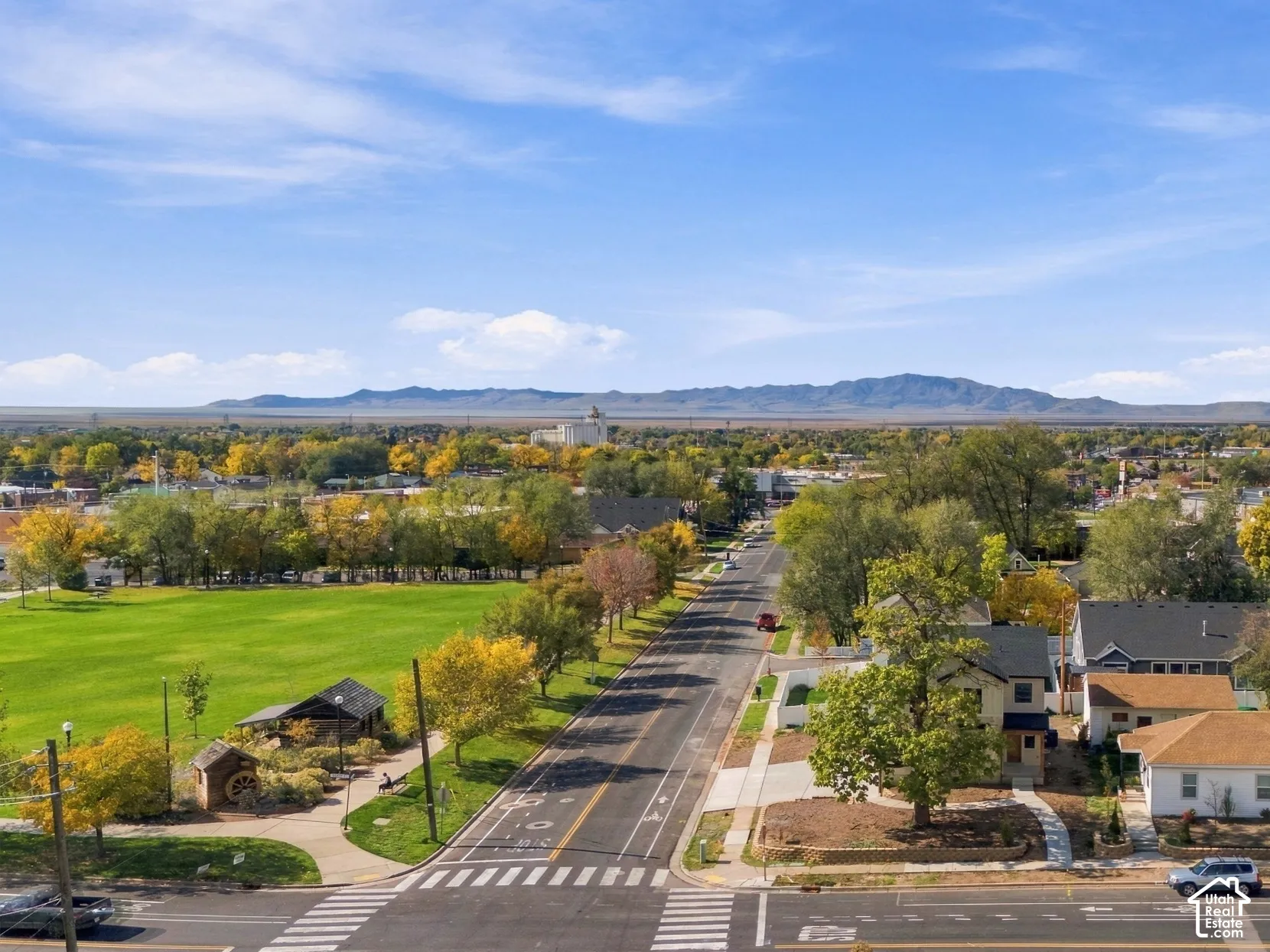 Aerial perspective featuring mountain backdrops, mature trees, and proximity to an expansive green space