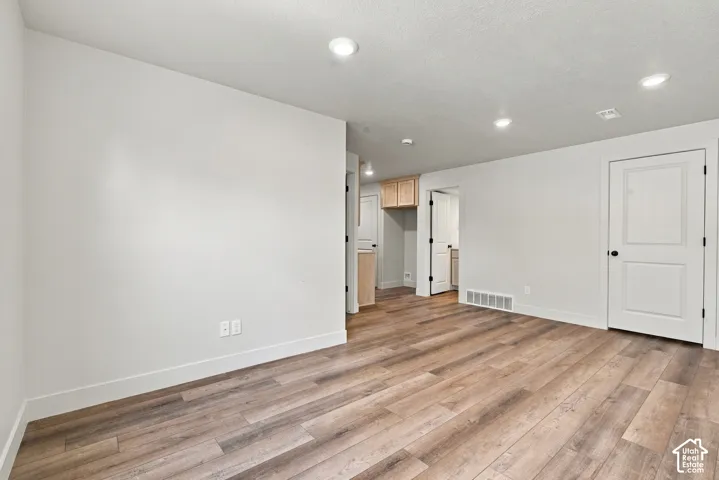 Interior space featuring wood-finish flooring, recessed lighting, and neutral wall paint with white panel doors and built-in upper cabinetry