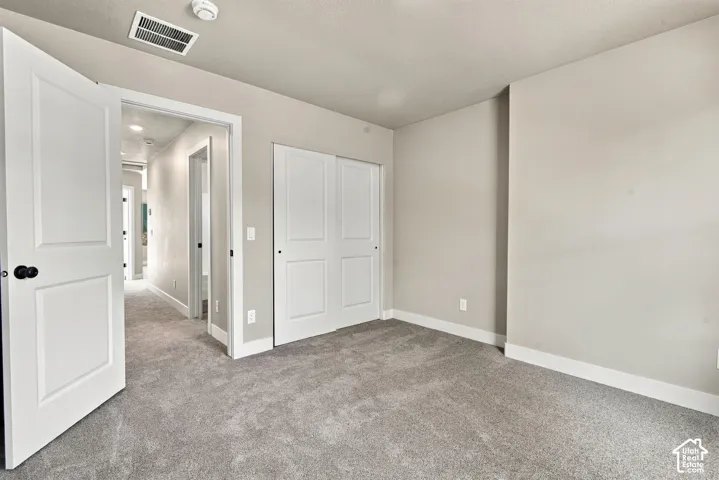 Neutral wall tones, wall-to-wall carpeting, two-panel interior doors, and closet with sliding doors