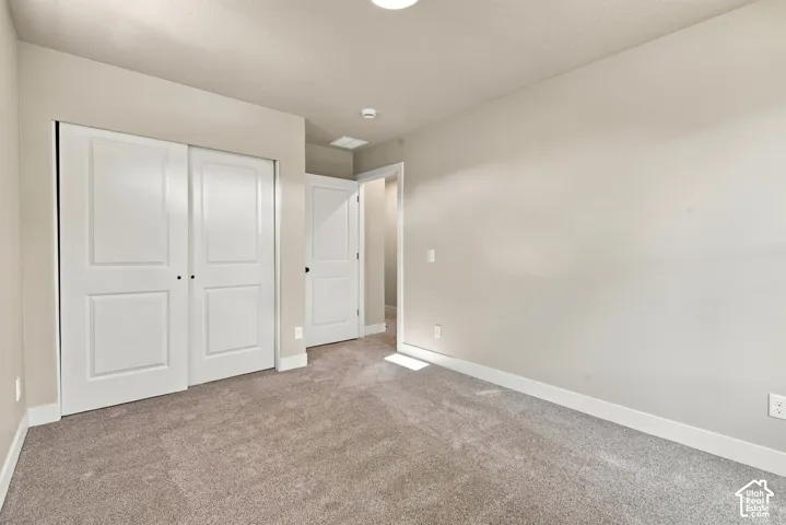 Neutral-toned carpeted interior featuring panel-style sliding closet doors and a multi-panel interior door