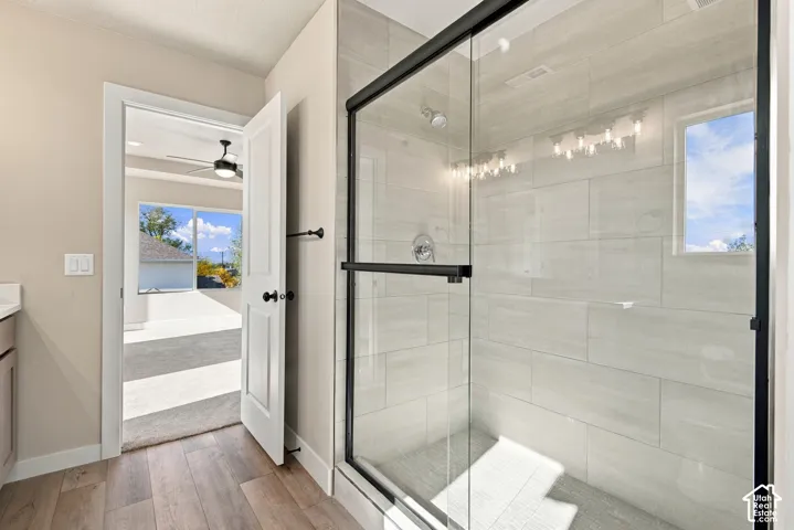 Walk-in shower featuring large-format horizontal tile surround, a frameless glass enclosure with matte black hardware, and wood-finish flooring