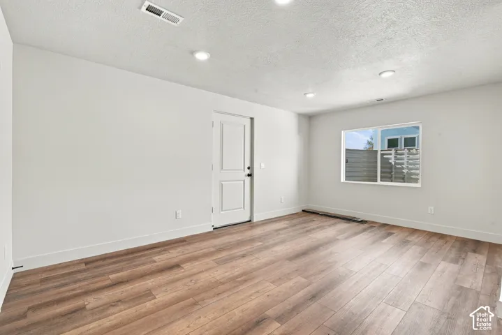 Neutral-toned interior featuring wood-finish flooring, recessed lighting, and a single-panel door