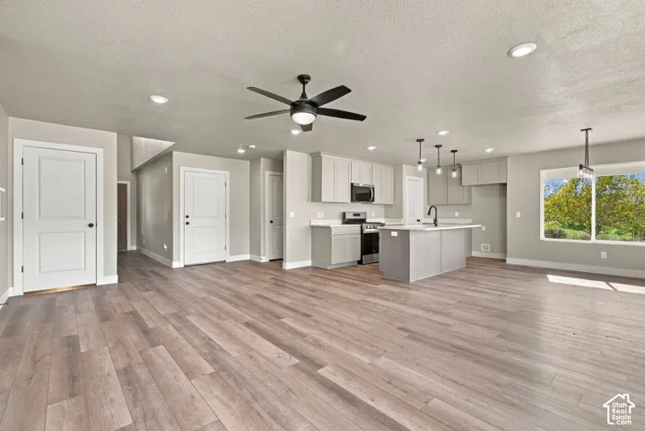 Open concept interior featuring wood-finish flooring, shaker-style cabinetry, a kitchen island, recessed lighting, and a ceiling fan