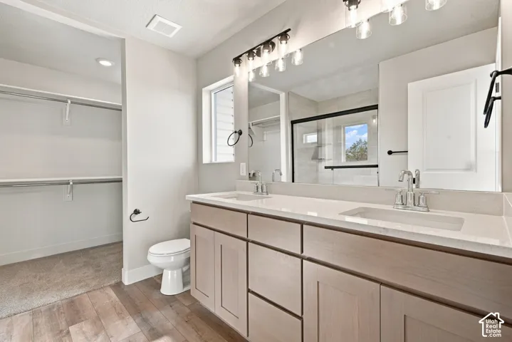 Double vanity with rectangular undermount sinks, stone-finish countertops, shaker-style cabinetry, and a full-width mirror
