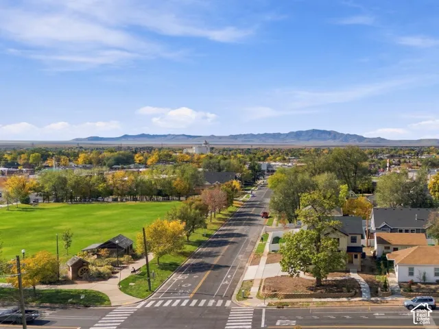 Aerial perspective featuring mountain backdrops, mature trees, and proximity to an expansive green space