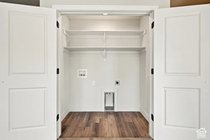 Utility closet featuring double panel doors, wood-finish flooring, two tiers of built-in shelving, and recessed laundry hookups