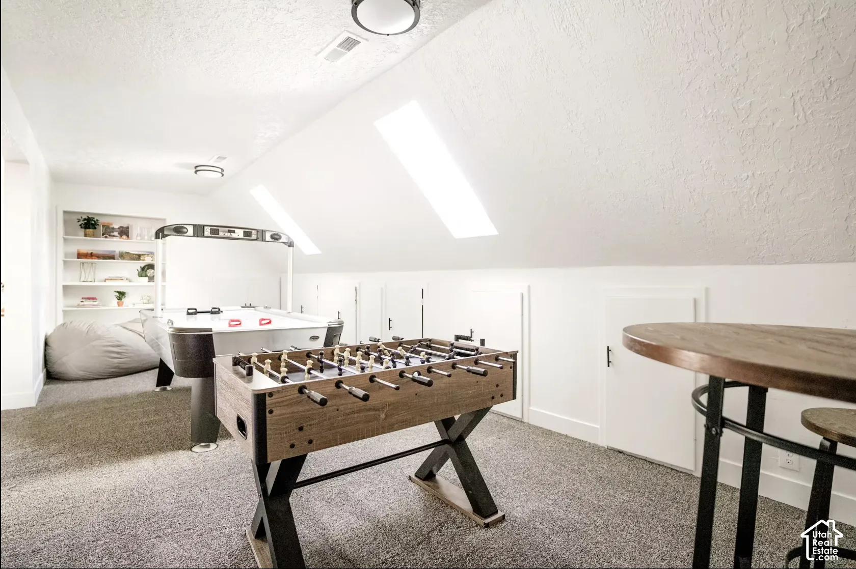 Upper-level room featuring sloped ceilings, two skylights, integrated shelving, and access panels for storage