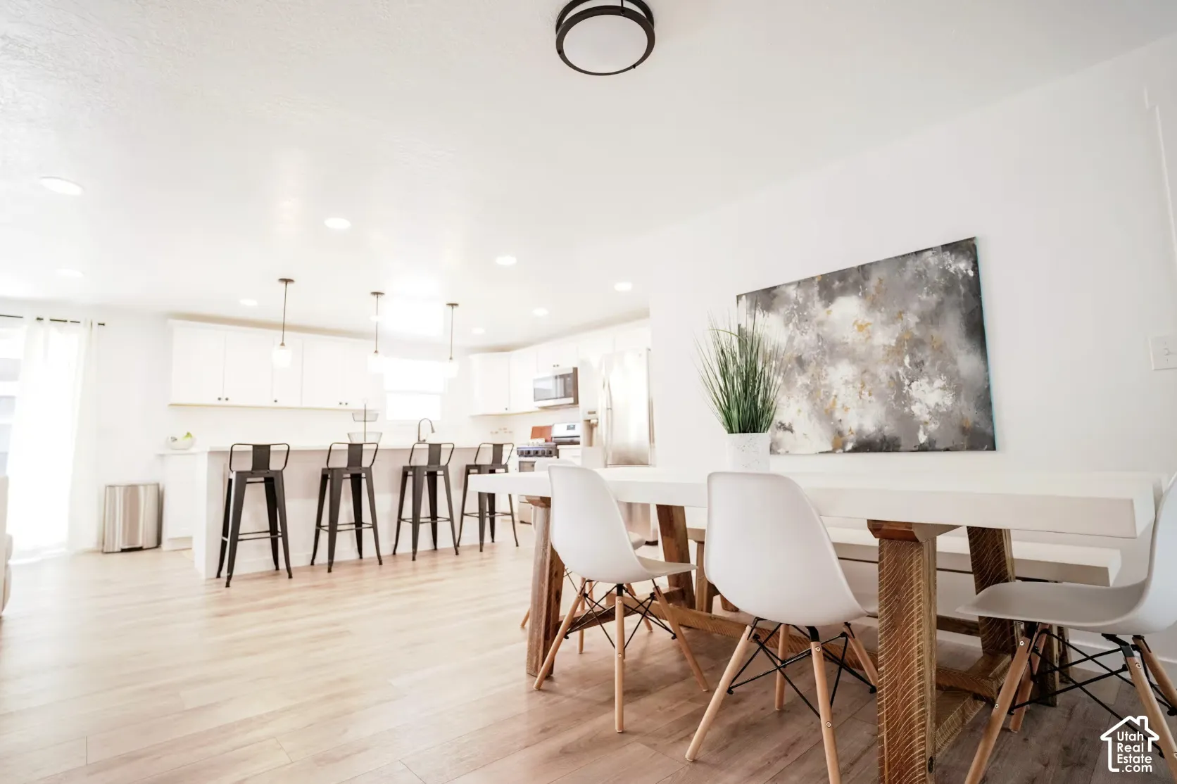 Kitchen featuring white cabinetry, wood-finish flooring, recessed lighting, and a breakfast bar