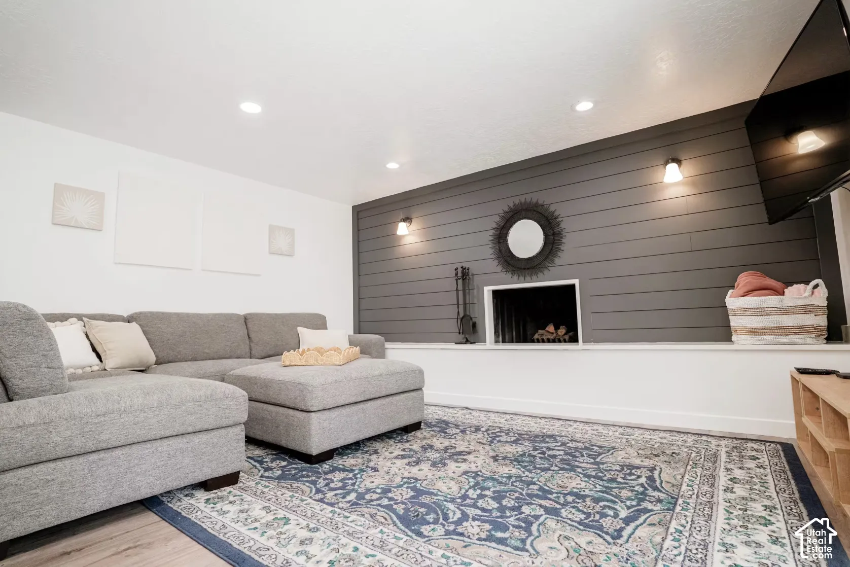 Charcoal horizontal shiplap accent wall featuring a masonry fireplace, recessed lighting, and wall-mounted sconces