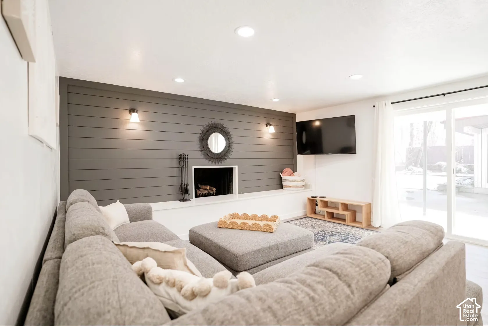 Living area featuring a horizontal shiplap accent wall, built-in fireplace, wall-mounted light fixtures, recessed ceiling lighting, and a sliding glass door