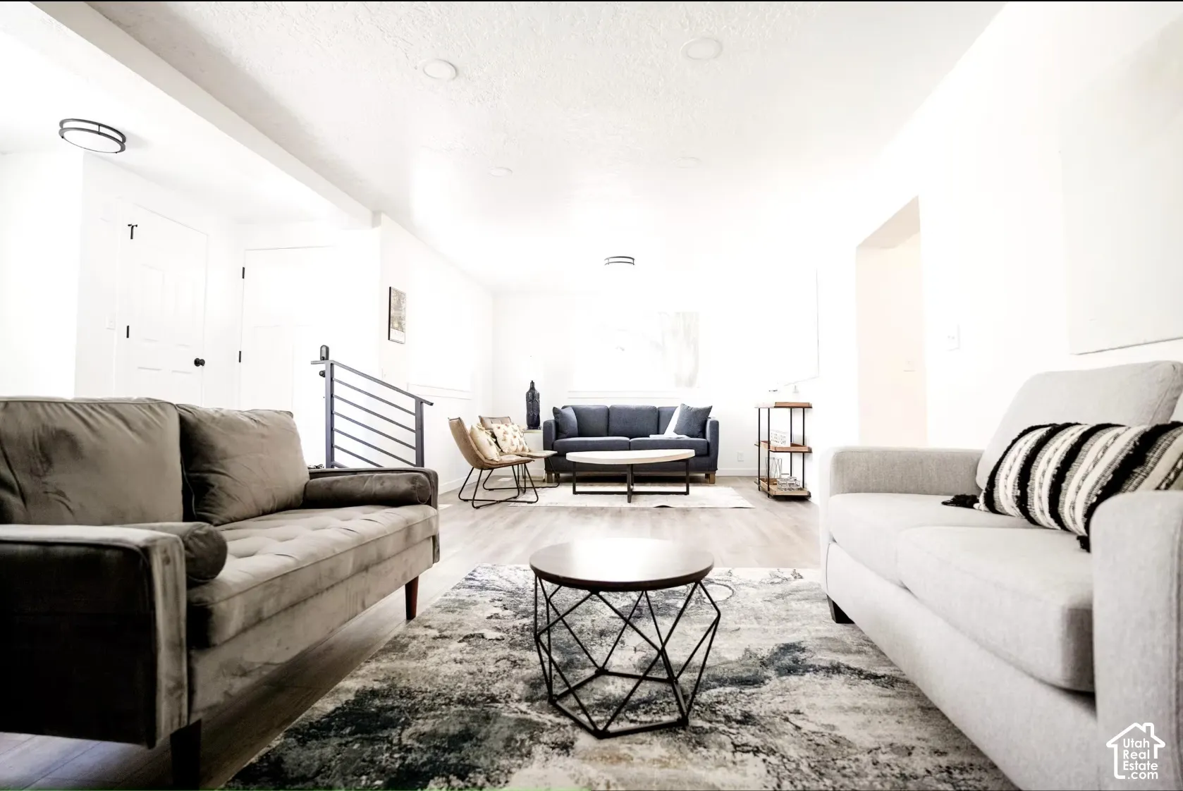 Open-concept interior featuring recessed lighting, wood-finish flooring, and a modern metal stair railing
