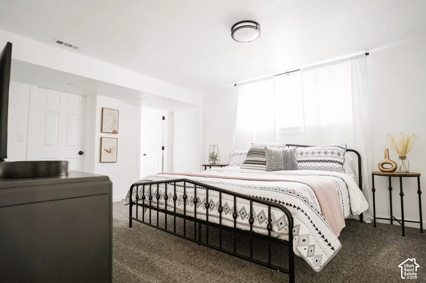 Bedroom featuring neutral wall-to-wall carpeting, white walls, two interior six-panel doors, and a central flush-mount ceiling light fixture