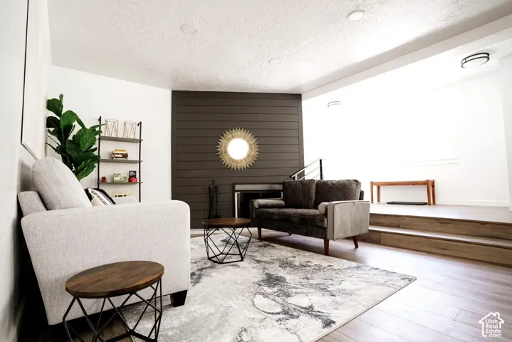 Living area featuring a horizontal plank accent wall, fireplace, wood-finish flooring, and recessed ceiling lighting