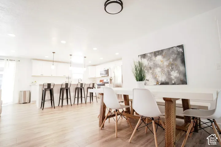 Kitchen featuring white cabinetry, wood-finish flooring, recessed lighting, and a breakfast bar