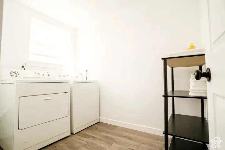 Dedicated laundry room featuring wood-finish flooring and a window providing natural light