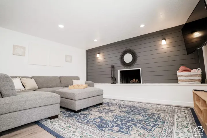 Charcoal horizontal shiplap accent wall featuring a masonry fireplace, recessed lighting, and wall-mounted sconces