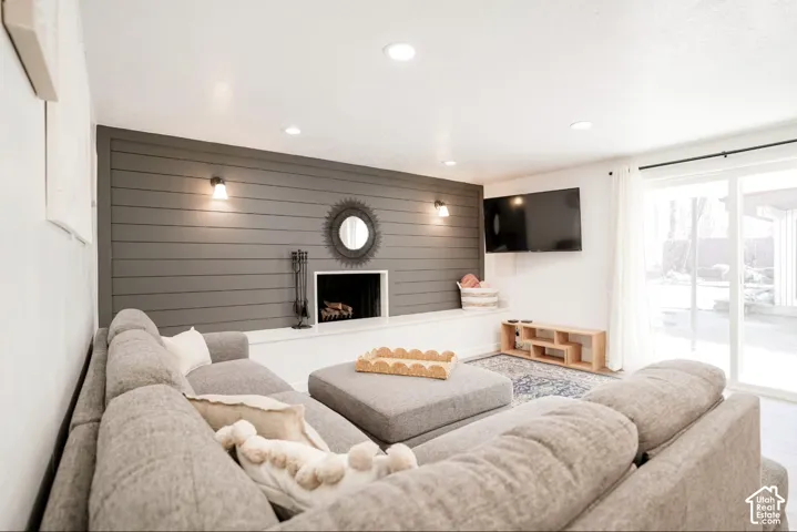 Living area featuring a horizontal shiplap accent wall, built-in fireplace, wall-mounted light fixtures, recessed ceiling lighting, and a sliding glass door
