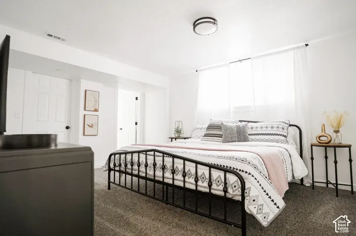 Bedroom featuring neutral wall-to-wall carpeting, white walls, two interior six-panel doors, and a central flush-mount ceiling light fixture