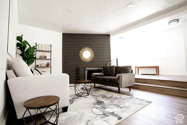 Living area featuring dark horizontal shiplap accent wall, fireplace with integrated metal surround, recessed ceiling lighting, and wood-finish flooring with a multi-level platform