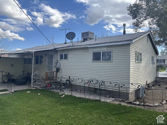 Light-colored vinyl siding, asphalt shingle roof, concrete patio, and fenced grass yard