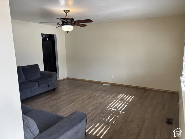 Neutral-toned interior space featuring wood-finish flooring and a central ceiling fan with an integrated light fixture