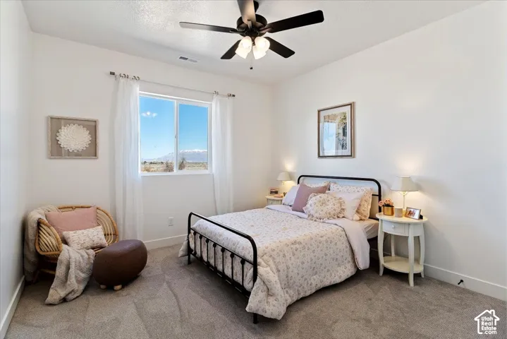 Neutral-toned wall-to-wall carpeting, multi-light ceiling fan, and large picture window with mountain backdrop