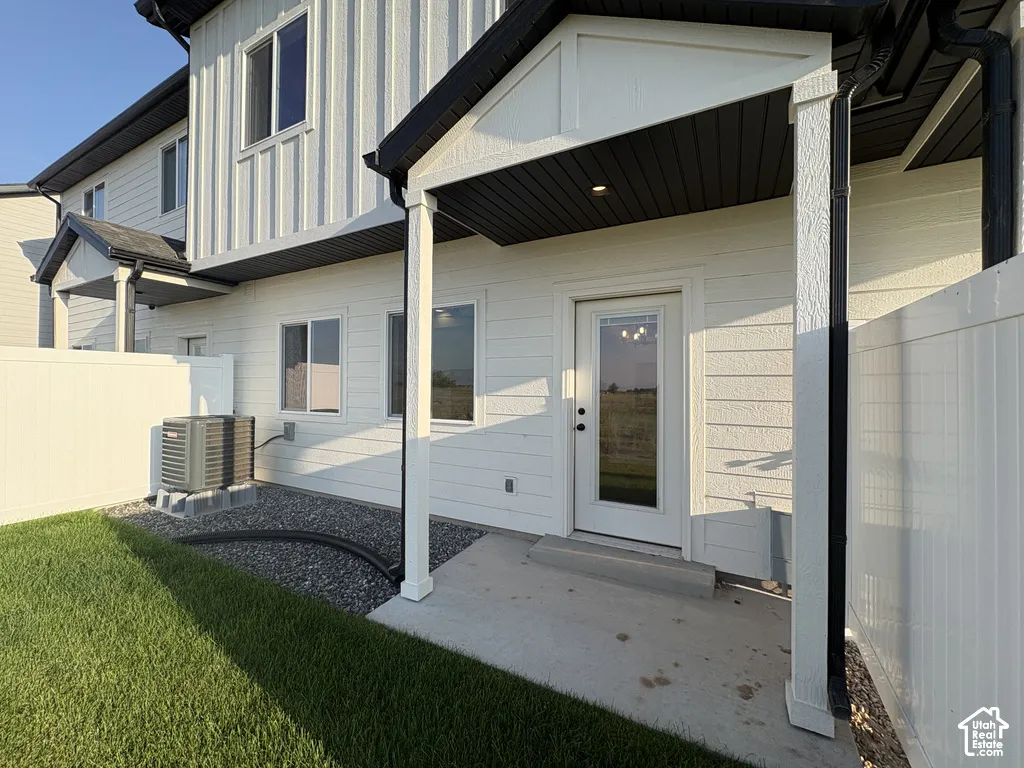 Exterior featuring white vertical board-and-batten and horizontal siding, covered concrete patio, recessed ceiling lighting, and white privacy fencing