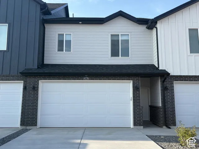 Modern exterior featuring a combination of horizontal lap siding and dark-toned brick masonry, a two-car garage, and asphalt shingle roofing