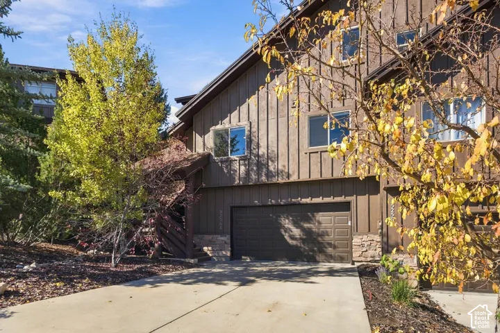 Multi-level exterior featuring vertical wood-style siding, stone veneer accents, and an attached multi-car garage with a concrete driveway