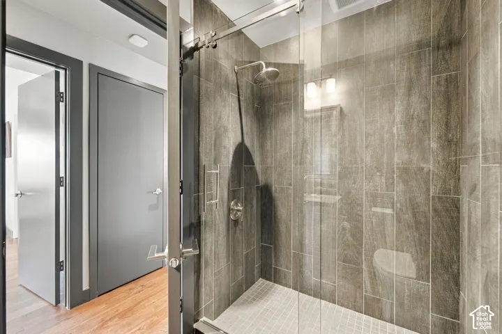 Walk-in shower featuring floor-to-ceiling large-format tile, frameless glass enclosure, polished chrome rainfall shower head, and a mosaic tile shower floor