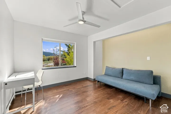 Interior space featuring wood-finish flooring, a ceiling fan with integrated lighting, and a large window showcasing mountain scenery