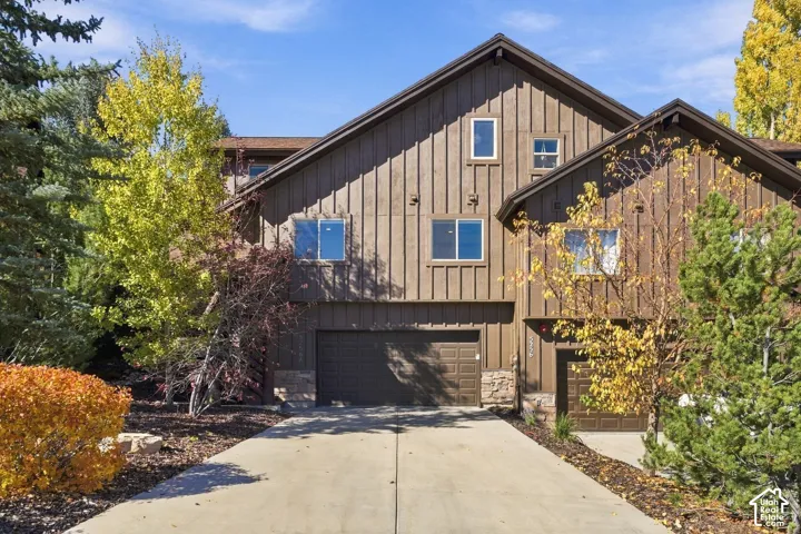 Exterior featuring vertical board-and-batten siding, stone foundation accents, multi-gabled roofline, dual garages, and a concrete driveway