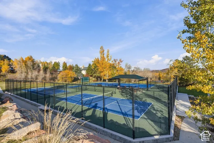 Multi-court recreational area featuring enclosed pickleball courts, a central covered pavilion, and perimeter chain-link fencing