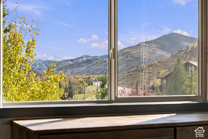 Large picture window framing mountain scenery and mature trees