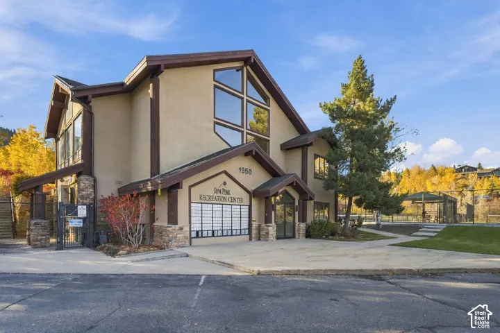Multi-level recreation center featuring stone foundation accents, wood-trim detailing, expansive geometric windows, and a paved exterior entryway