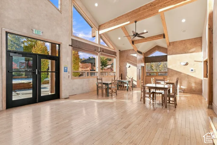 Vaulted ceilings with exposed timber beams, expansive floor-to-ceiling windows, wood-finish flooring, and recessed lighting