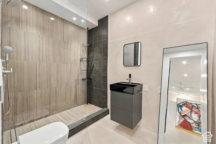 Walk-in shower with vertical wood-finish tile, dark charcoal accent tile, wall-mounted matte hardware, and glass enclosure, featuring a floating vanity with a dark glass vessel sink and integrated faucet